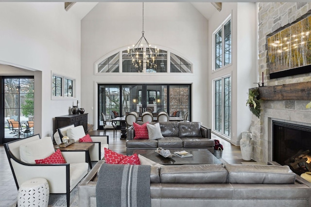 living room with an inviting chandelier, wood-type flooring, a fireplace, and high vaulted ceiling