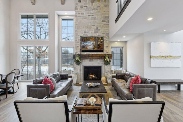 living room featuring a stone fireplace, hardwood / wood-style floors, and a high ceiling