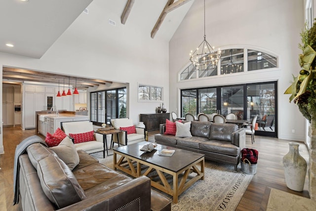 living room featuring a notable chandelier, high vaulted ceiling, light hardwood / wood-style floors, and beamed ceiling