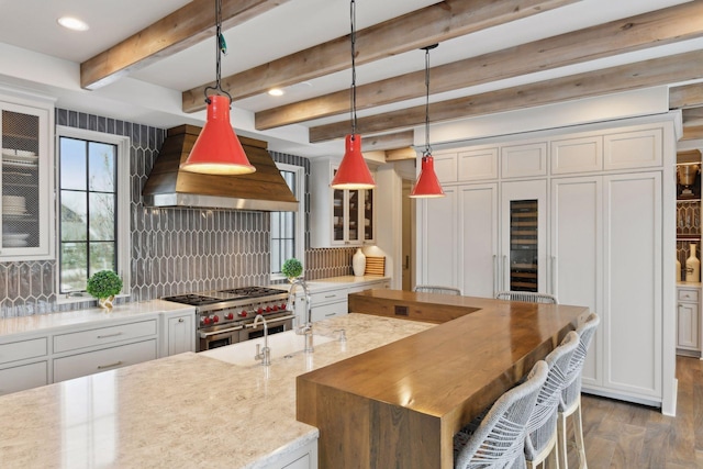 kitchen with white cabinetry, double oven range, hanging light fixtures, light stone countertops, and custom exhaust hood