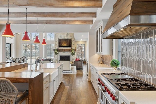 kitchen featuring pendant lighting, white cabinetry, sink, custom exhaust hood, and double oven range