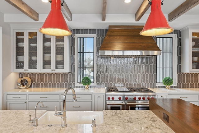 kitchen with premium range hood, sink, white cabinets, decorative backsplash, and double oven range