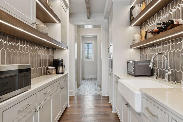 kitchen with white cabinetry, dark hardwood / wood-style flooring, sink, and beamed ceiling