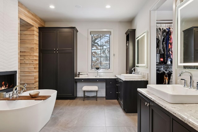 bathroom with vanity, a fireplace, a bathing tub, and tile patterned flooring