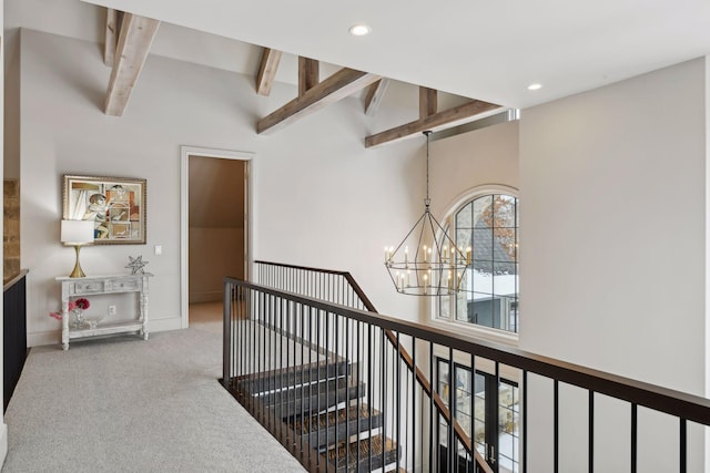 hallway with beam ceiling, carpet floors, and a chandelier