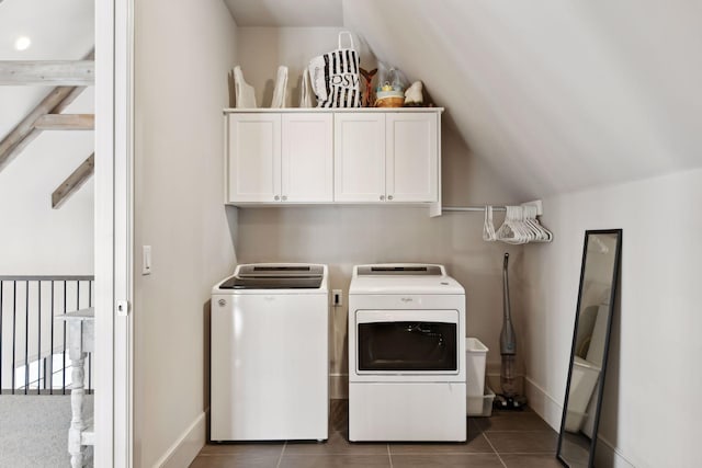 clothes washing area with dark tile patterned flooring, washing machine and dryer, and cabinets