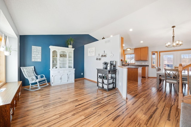interior space featuring visible vents, light wood-style floors, baseboards, a notable chandelier, and vaulted ceiling