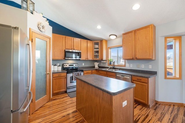 kitchen with a sink, dark countertops, stainless steel appliances, and light wood finished floors