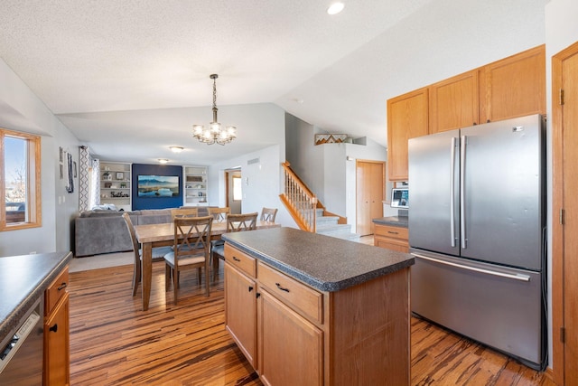 kitchen with dark countertops, vaulted ceiling, wood finished floors, a notable chandelier, and stainless steel appliances