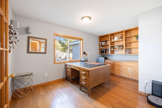 office area with baseboards, a textured ceiling, and light wood-style flooring
