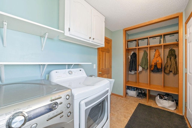 washroom featuring washing machine and clothes dryer, a textured ceiling, and cabinet space
