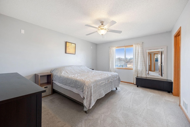 carpeted bedroom with a ceiling fan, a textured ceiling, visible vents, and baseboards