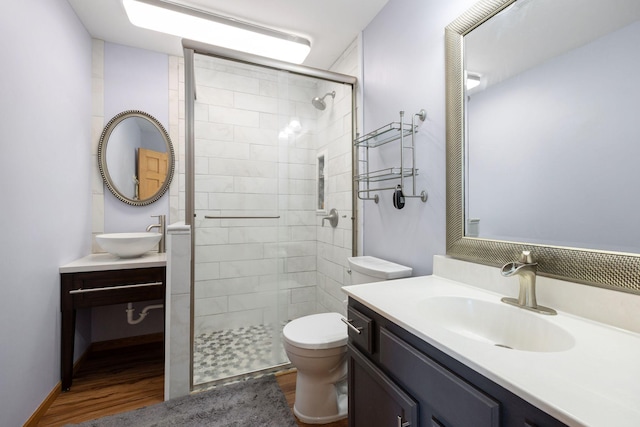 full bathroom with a sink, a shower stall, toilet, and wood finished floors