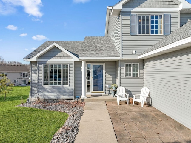 exterior space featuring a lawn, a patio, and a shingled roof