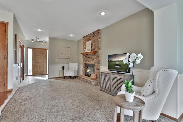 sitting room featuring a brick fireplace and light colored carpet