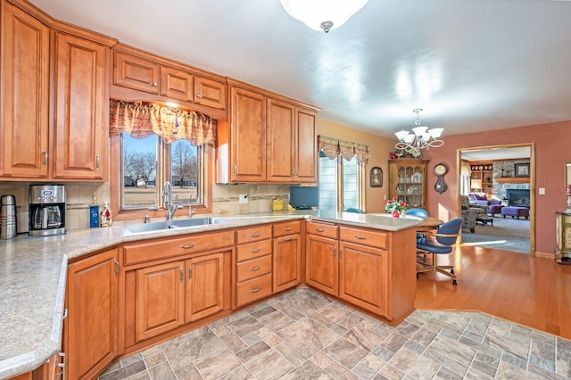 kitchen featuring sink, an inviting chandelier, a fireplace, decorative light fixtures, and kitchen peninsula