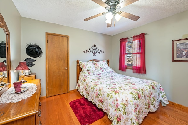 bedroom with ceiling fan, light hardwood / wood-style flooring, and a textured ceiling