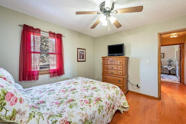 bedroom with ceiling fan, light hardwood / wood-style floors, and a textured ceiling