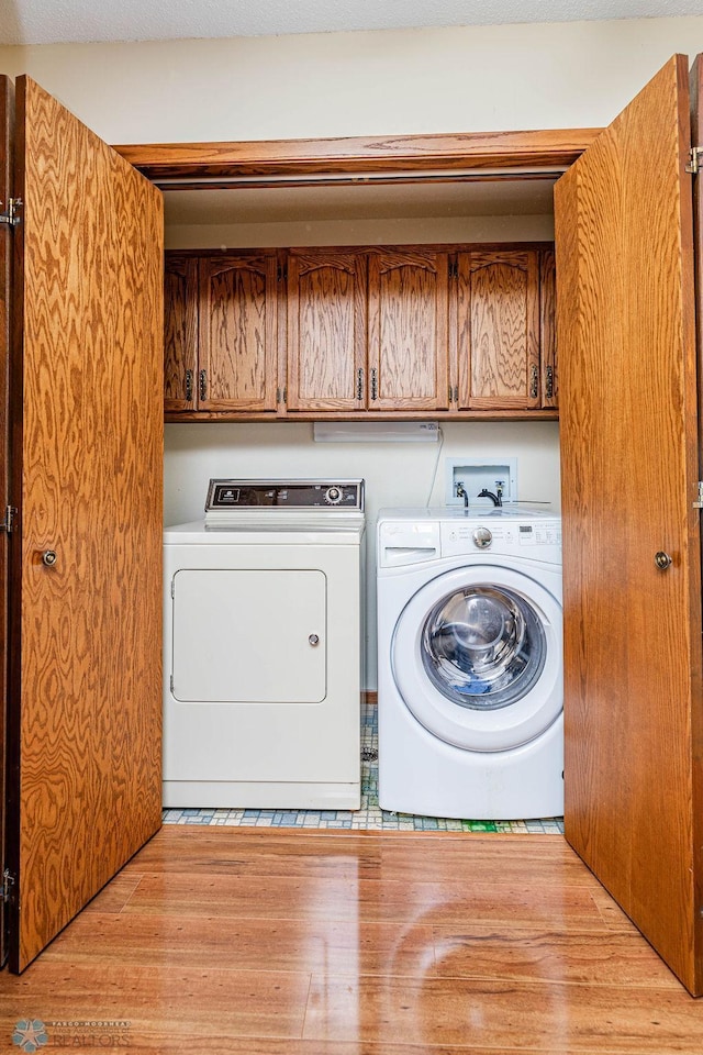 laundry area with wood finished floors, cabinet space, and washer and dryer