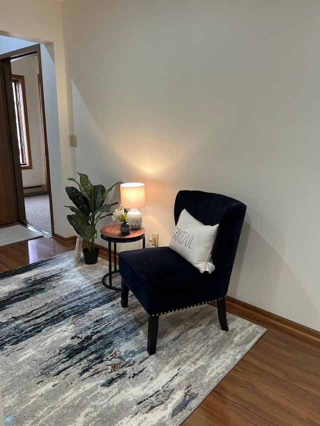 sitting room featuring baseboards, baseboard heating, and wood finished floors