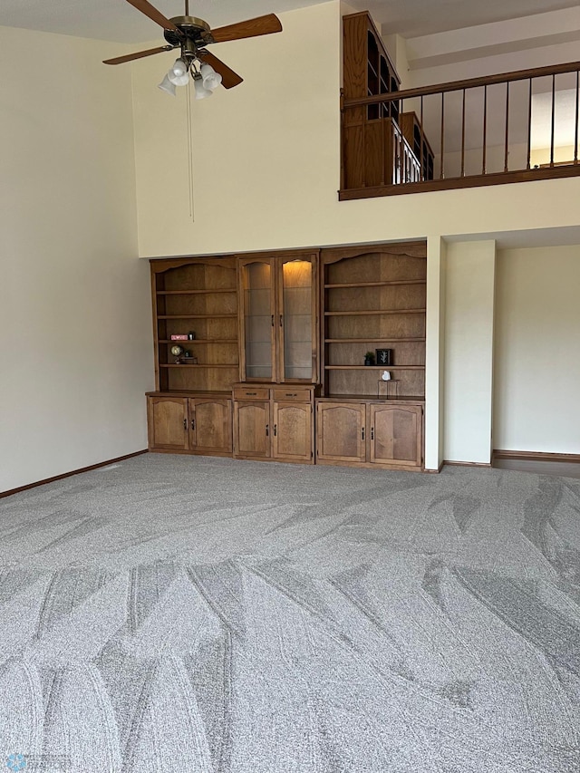 living area with carpet floors, a high ceiling, and baseboards