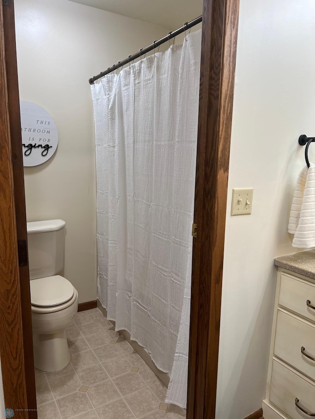 bathroom featuring baseboards, toilet, a shower with curtain, tile patterned flooring, and vanity