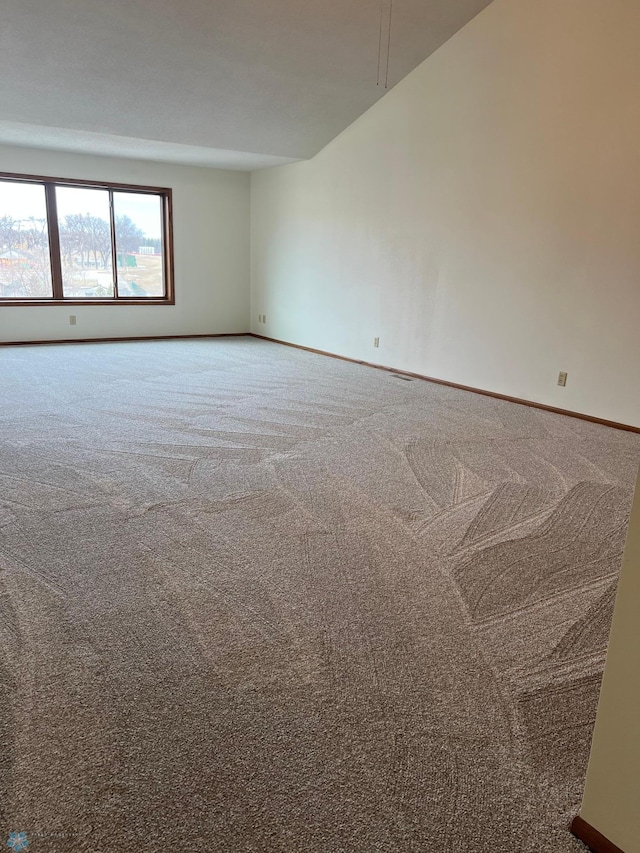 carpeted empty room featuring baseboards