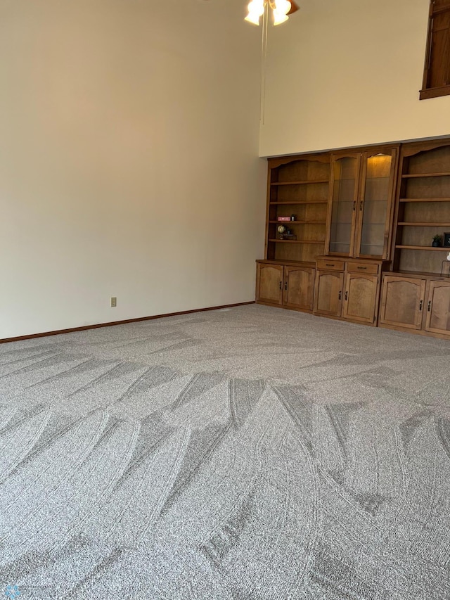 living room with light carpet, a towering ceiling, and baseboards