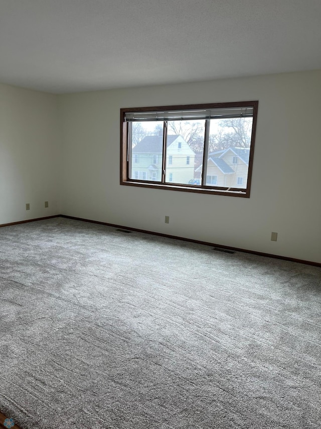 empty room featuring carpet flooring, visible vents, and baseboards