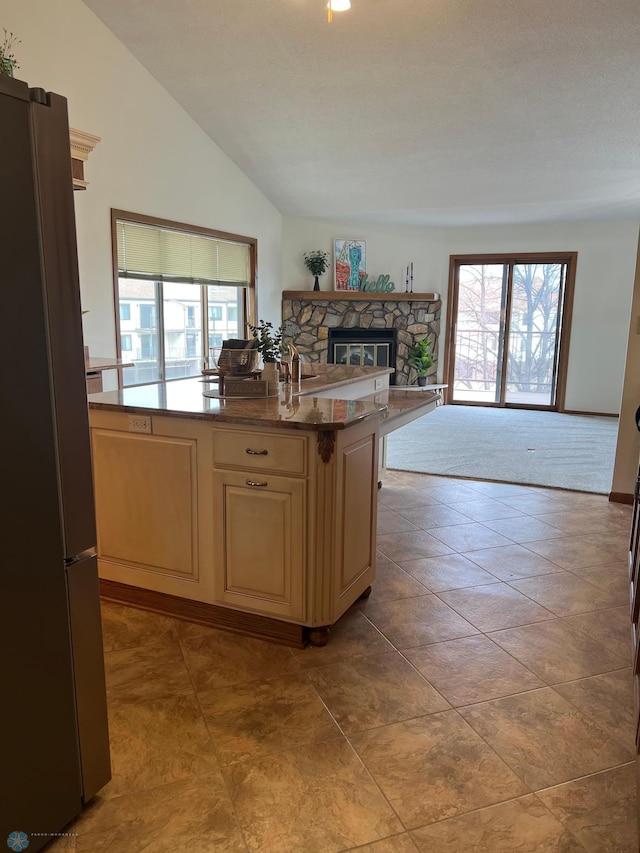 kitchen with cream cabinetry, a fireplace, freestanding refrigerator, and a healthy amount of sunlight