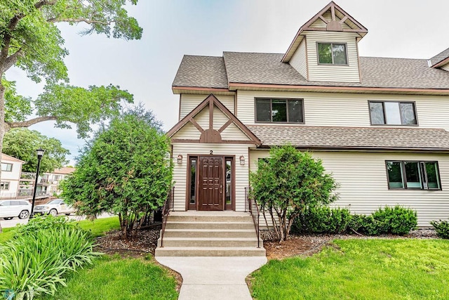 view of front of home with a shingled roof and a front lawn