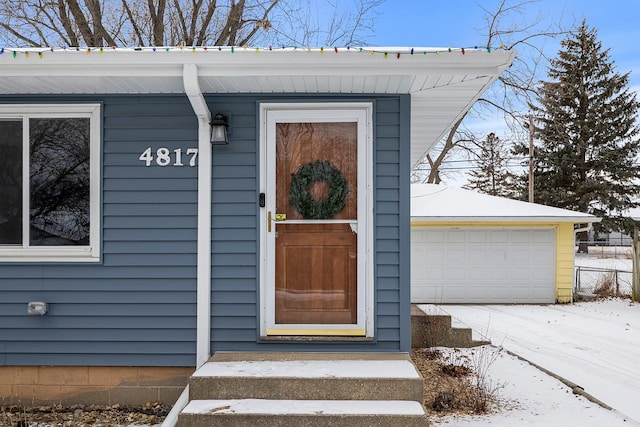 snow covered property entrance featuring a garage