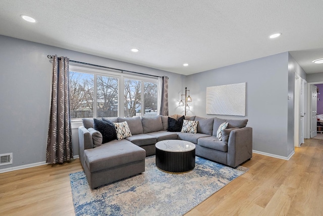 living room featuring a textured ceiling and light wood-type flooring