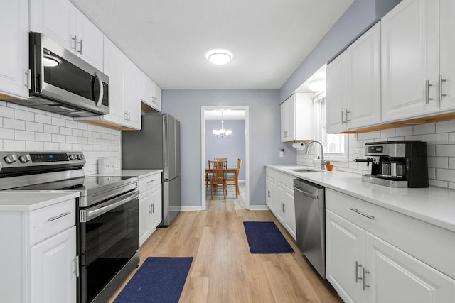 kitchen with stainless steel appliances, light hardwood / wood-style floors, sink, and white cabinets