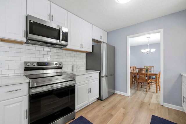 kitchen featuring decorative light fixtures, light hardwood / wood-style flooring, white cabinets, stainless steel appliances, and backsplash