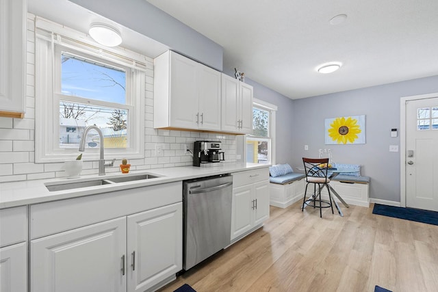 kitchen with sink, white cabinetry, dishwasher, light hardwood / wood-style floors, and backsplash