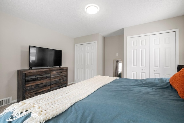 bedroom with two closets and a textured ceiling