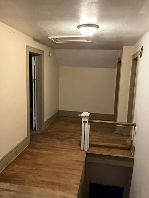 hallway featuring lofted ceiling and dark wood-type flooring