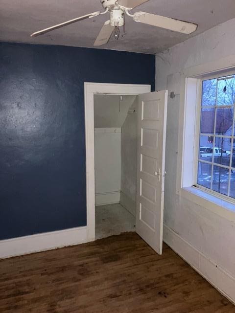 empty room featuring ceiling fan, baseboards, and wood finished floors