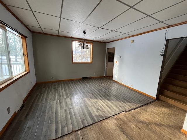 unfurnished room featuring crown molding, wood finished floors, baseboards, and a drop ceiling