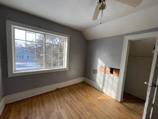 unfurnished bedroom featuring a closet, baseboards, vaulted ceiling, a ceiling fan, and light wood finished floors