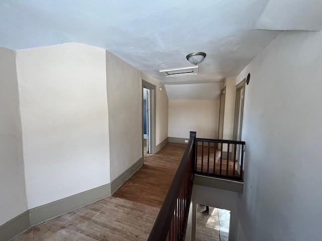 corridor featuring visible vents, baseboards, an upstairs landing, attic access, and wood finished floors