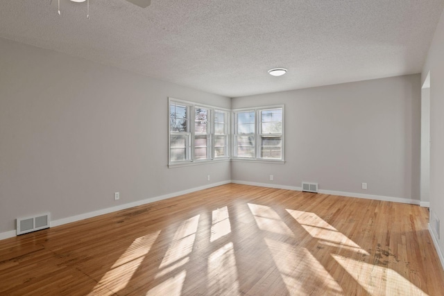 spare room featuring ceiling fan, light hardwood / wood-style floors, and a textured ceiling