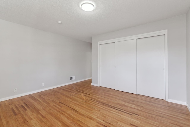 unfurnished bedroom with a closet, a textured ceiling, and light hardwood / wood-style flooring