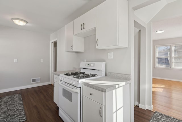 kitchen featuring dark wood-type flooring, white gas range, and white cabinets