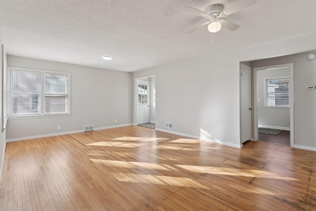 empty room with ceiling fan, a textured ceiling, and light wood-type flooring