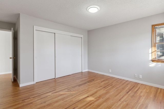 unfurnished bedroom with light hardwood / wood-style floors, a closet, and a textured ceiling