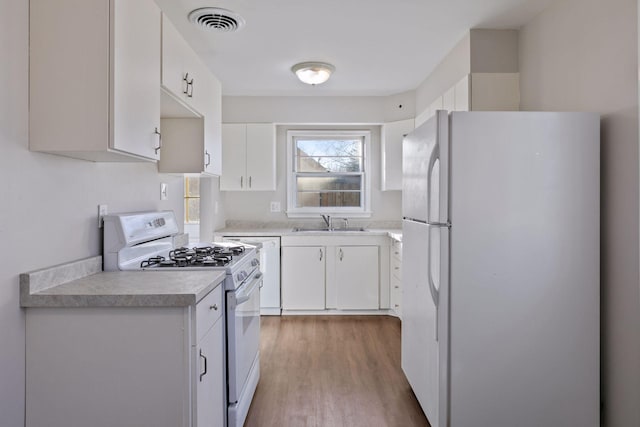 kitchen with sink, white cabinets, white appliances, and light hardwood / wood-style floors