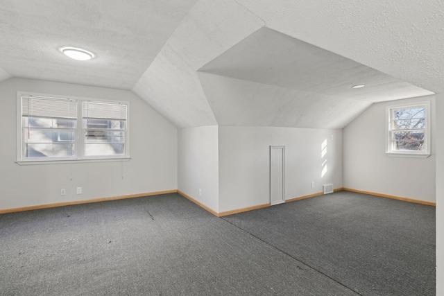 bonus room with lofted ceiling, carpet floors, and a textured ceiling