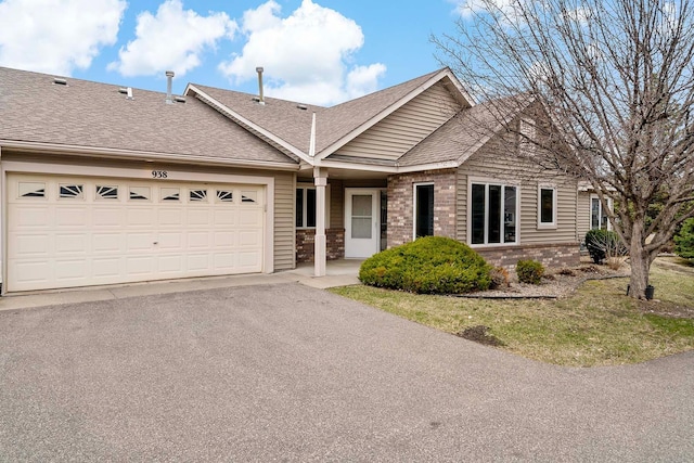 ranch-style house with an attached garage, a shingled roof, aphalt driveway, and brick siding